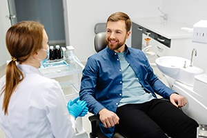 Young man talking to female dentist during exam