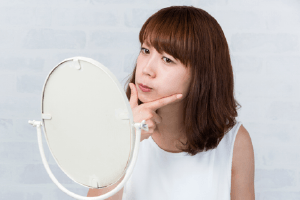 Woman looking at jaw alignment in mirror