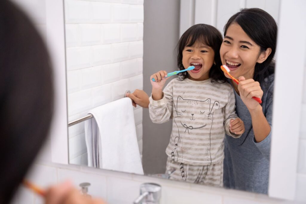 A mother and child brushing their teeth together